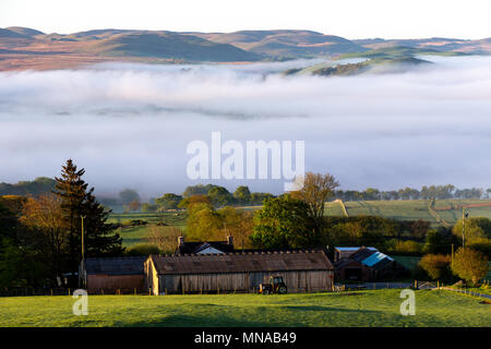 Ystrad Meurig, Ceredigion, Wales, Regno Unito 15 maggio 2018 UK Meteo: mattina nebbia avvolge la parte superiore raggiunge di Teifi Valley, a fianco del bordo del Cambriano montagne in Galles. Come il sole brilla luminoso sopra il piccolo borgo rurale di Ystrad Meurig. Credito: Ian Jones/Alamy Live News Foto Stock