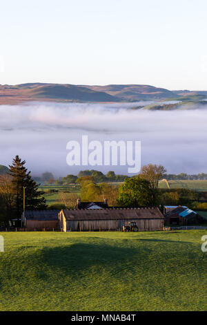 Ystrad Meurig, Ceredigion, Wales, Regno Unito 15 maggio 2018 UK Meteo: mattina nebbia avvolge la parte superiore raggiunge di Teifi Valley, a fianco del bordo del Cambriano montagne in Galles. Come il sole brilla luminoso sopra il piccolo borgo rurale di Ystrad Meurig. Credito: Ian Jones/Alamy Live News Foto Stock