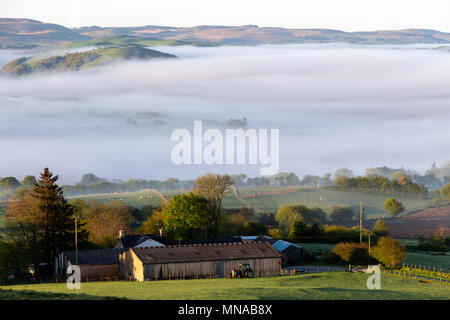 Ystrad Meurig, Ceredigion, Wales, Regno Unito 15 maggio 2018 UK Meteo: mattina nebbia avvolge la parte superiore raggiunge di Teifi Valley, a fianco del bordo del Cambriano montagne in Galles. Come il sole brilla luminoso sopra il piccolo borgo rurale di Ystrad Meurig. Credito: Ian Jones/Alamy Live News Foto Stock