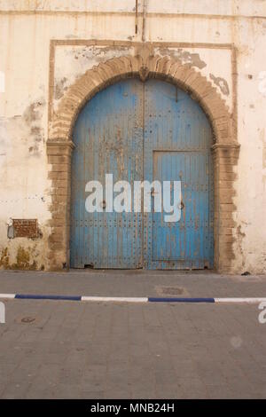 Una vecchia porta blu che ha lo sbiadimento del colore e la pelatura a Essaouira, Marocco Foto Stock