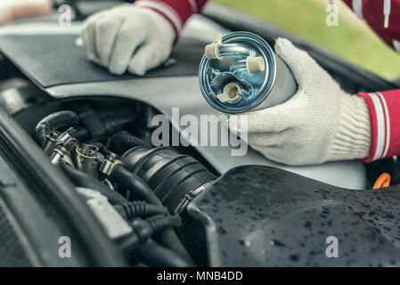 Un meccanico automatico sostituisce un auto del filtro del carburante. Foto Stock