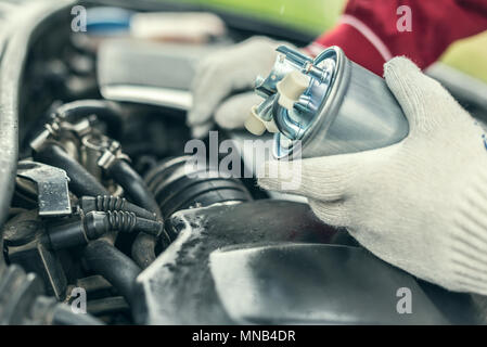 Un meccanico automatico sostituisce un auto del filtro del carburante. Foto Stock