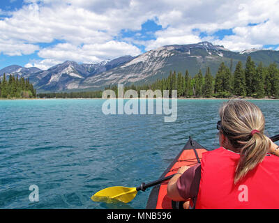 Donna con kayak gonfiabili rosso kayak sul lago di Edith, Jasper, montagne rocciose, Canada Foto Stock