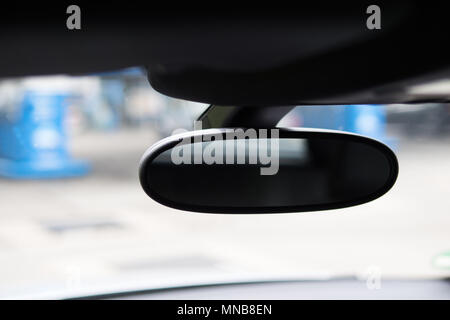 Specchio auto visto dall'interno di un automobile e uno sfondo sfocato. Messa a fuoco selettiva. Close up. Foto Stock