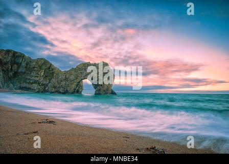 Il sole sorge oltre la Manica a Durdle porta sul Jurassic Coast in Dorset Foto Stock