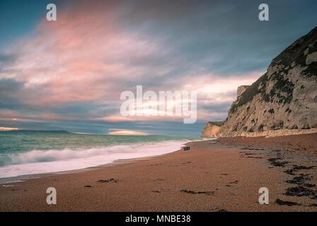 Il sole sorge oltre la Manica a Durdle porta sul Jurassic Coast in Dorset Foto Stock