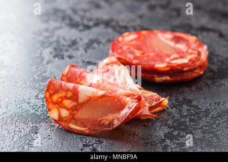 Fette di salame chorizo insaccato su tavola nera. Foto Stock