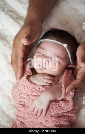 African American prendersi cura di bianco neonato. Padre mani tenere bambina Foto Stock