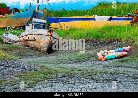 Un vecchio abbandonato marciume barca si siede in un campo fangoso che sembrano essere un cimitero di vecchie imbarcazioni. Visto dal percorso a piedi lungo Kachemak Bay . Foto Stock