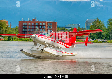 Un rosso e bianco idrovolante decolla sul lago il cofano ad Anchorage in Alaska Foto Stock