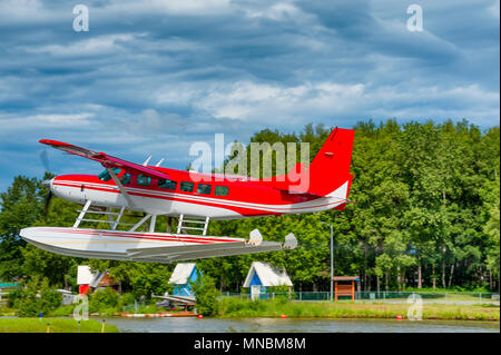 Un rosso e bianco idrovolante decolla sul lago il cofano ad Anchorage in Alaska Foto Stock