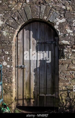 Una vecchia porta di legno insieme in un vecchio muro di pietra Foto Stock