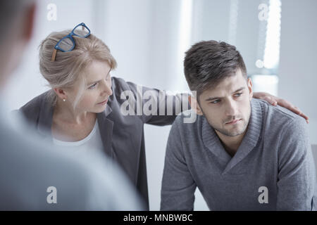 Lo psicologo sostiene la giovane uomo che soffre di depressione Foto Stock