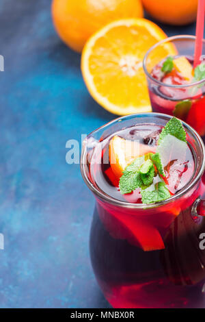 Analcoliche rinfrescante Sangria spagnola dalla varietà di frutti di agrumi arancio Melograno acini di uva e menta fresca nella brocca e bicchiere alto su B Foto Stock