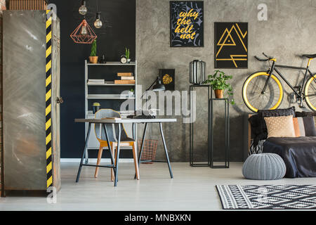 Appartamento in stile industriale con letto, scrivania e armadio metallico Foto Stock