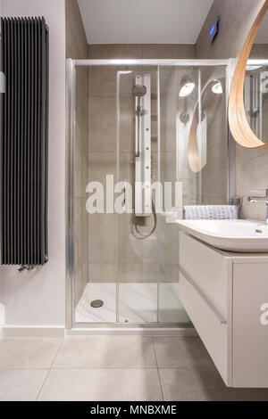 Luce di bagno con box doccia e piastrelle grigie Foto Stock