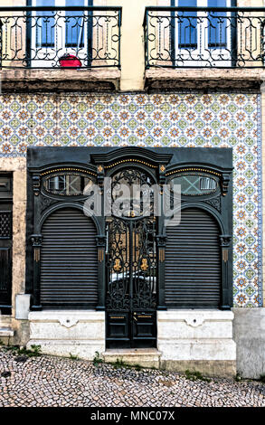 La facciata della casa cittadina in Martim Moniz ornato di porta nera con decorazioni in oro, circondato da con piastrelle di ceramica in parete Foto Stock