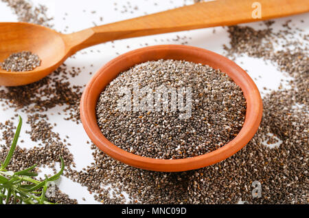 Ciotola di sani semi di Chia e il cucchiaio di legno su sfondo bianco Foto Stock