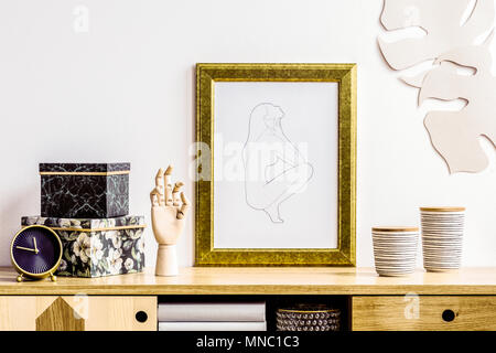 Grande armadio, scatole floreali, a mano in legno e un poster di una donna in una cornice dorata in salotto Foto Stock