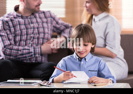 Close-up di sorridere boy il disegno di una foto durante la terapia per bambini autistici Foto Stock