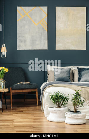 Grande e comodo letto sotto il poster sulla parete scura con stampaggio e  tra piante in camera da letto interno Foto stock - Alamy