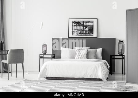Letto bianco tra le tabelle con lanterne in hotel bedroom interno con poster su grigio testata Foto Stock