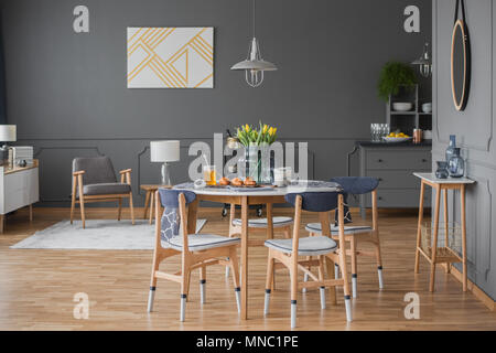 Spaziosa sala da pranzo interno con muro grigio stampaggio, tavolo, sedie, tulipani e moderna lampada Foto Stock