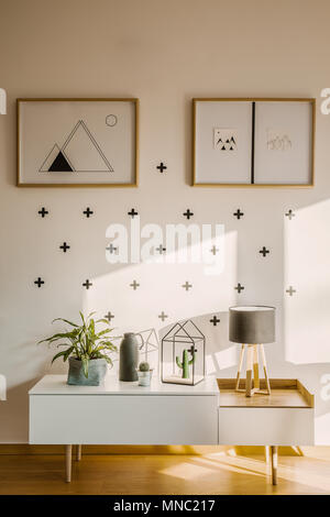 Incorniciato poster su una parete bianca con il segno più pattern e una credenza scandinavo in una moderna e luminosa camera da letto interno Foto Stock