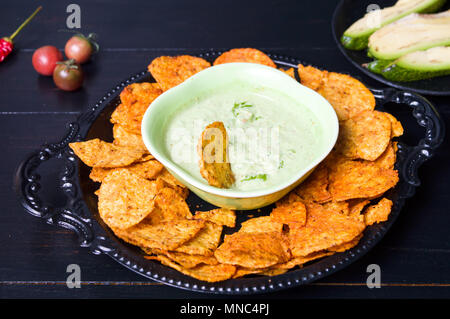 Tortilla chips con dip di Avocado servito su una piastra Foto Stock
