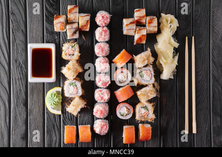 Ampia serie di rotoli con guarnire e hashi sul piatto di legno Foto Stock