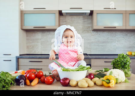 Una bambina in una chef hat prepara in cucina. Foto Stock