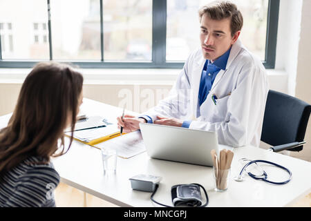 Giovane medico ascoltando la sua paziente con rispetto e dedizione Foto Stock