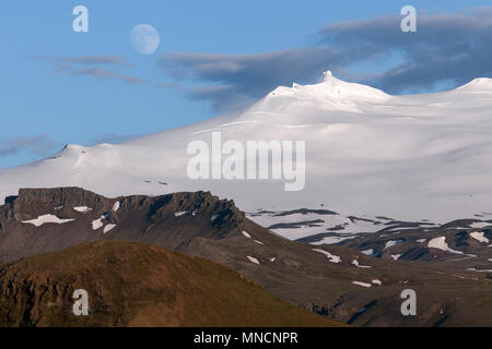 Coperte di neve vulcano Snaefell con ghiacciaio Snaefellsjökul e luna piena, paesaggio vulcanico vicino Hellissandur Foto Stock