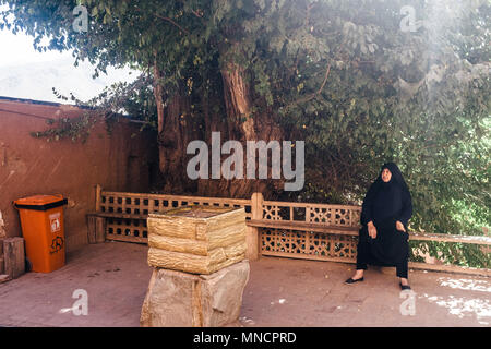 Abyaneh, Iran - 13 Ottobre 2017: una donna che indossa un Hijab è seduta su una panchina. Foto Stock