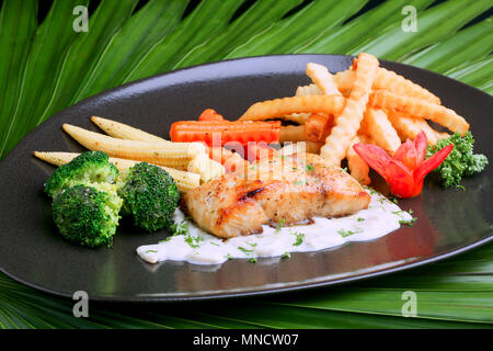 Bistecca di salmone sulla piastra con corn chips e pomodori. Foto Stock