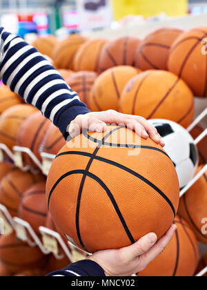 Acquirente con le mani la pallacanestro nel negozio di articoli sportivi Foto Stock