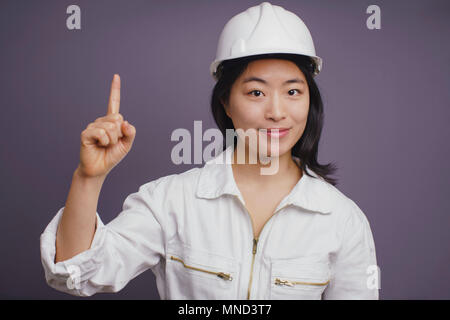 Ritratto di certi giovani femmine lavoratore edile indossando hardhat rivolta verso l'alto Foto Stock