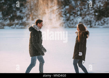 Vista laterale di giocoso l uomo e la donna per godere nella neve Foto Stock