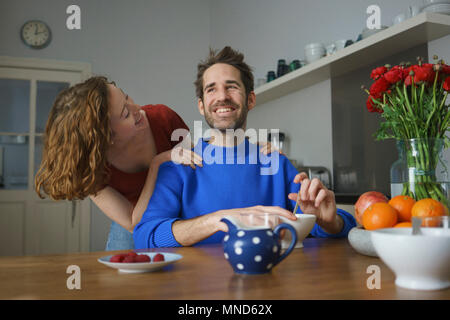 Allegro metà adulto giovane a tavola con colazione in camera Foto Stock