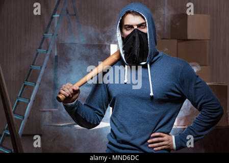 Hooligan con bat in dark room Foto Stock