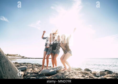 Relazione tra tre giovani bellezza donna balli sulla spiaggia durante una vacanza. Tramonto a Tenerife, effetto flare e filtro caldo. Foto Stock