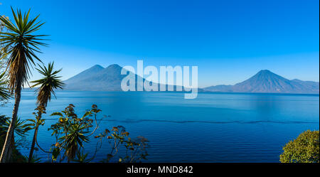 Vista dal lago Atitlan nelle prime ore del mattino, cieli blu e acqua limpida, bellissimo lago magico con i vulcani e i popoli indigeni Nel altopiano di gu Foto Stock