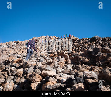 Scalatore scendendo dal ripido percorso dal vertice del cono del vulcano attivo El Teide mentre altri scalatori ascend Tenerife - Isole Canarie Foto Stock