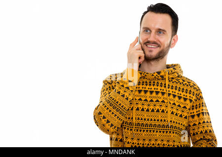 Studio shot di felice giovane uomo sorridente mentre parlano al telefono cellulare e di pensiero Foto Stock