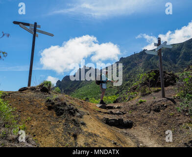 Una femmina di walker sale a un incrocio di sentieri con molti segni waymarker alta sopra Hermigua sulla costa nord di La Gomera nelle isole Canarie Foto Stock