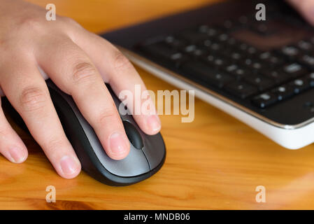 Persone mano utilizzando un mouse del computer su una scrivania in legno Foto Stock