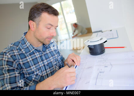 Builder andando oltre i piani di costruzione Foto Stock