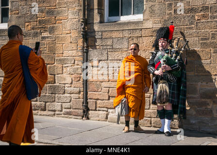 Il Royal Mile di Edimburgo, 16 maggio 2018. Turisti che si godono il sole sulla Royal Mile di Edimburgo, Scozia, Regno Unito. I turisti affollano il Royal Mile, compreso un gruppo di monaci vestiti di arancione brillante vesti. Un monaco buddista è di scattare una foto di un monaco buddista in piedi accanto a una delle cornamuse scozzesi player vestito con un kilt Foto Stock