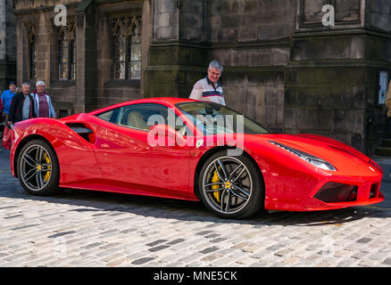 Il Royal Mile di Edimburgo, 16 maggio 2018. Turisti che si godono il sole sulla Royal Mile di Edimburgo, Scozia, Regno Unito. Un uomo cammina da un luminoso rosso Ferrari 488 GTB sport coupe auto parcheggiate su una doppia linea gialla sul lastricato della Royal Mile accanto alla Cattedrale di St Giles, conferendole un look invidiabile Foto Stock