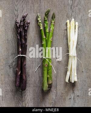 Viola, Verde e asparagi bianchi steli su una superficie in legno Foto Stock